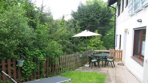 A patio with a table and chairs, a sun umbrella, and a reclining chair.
