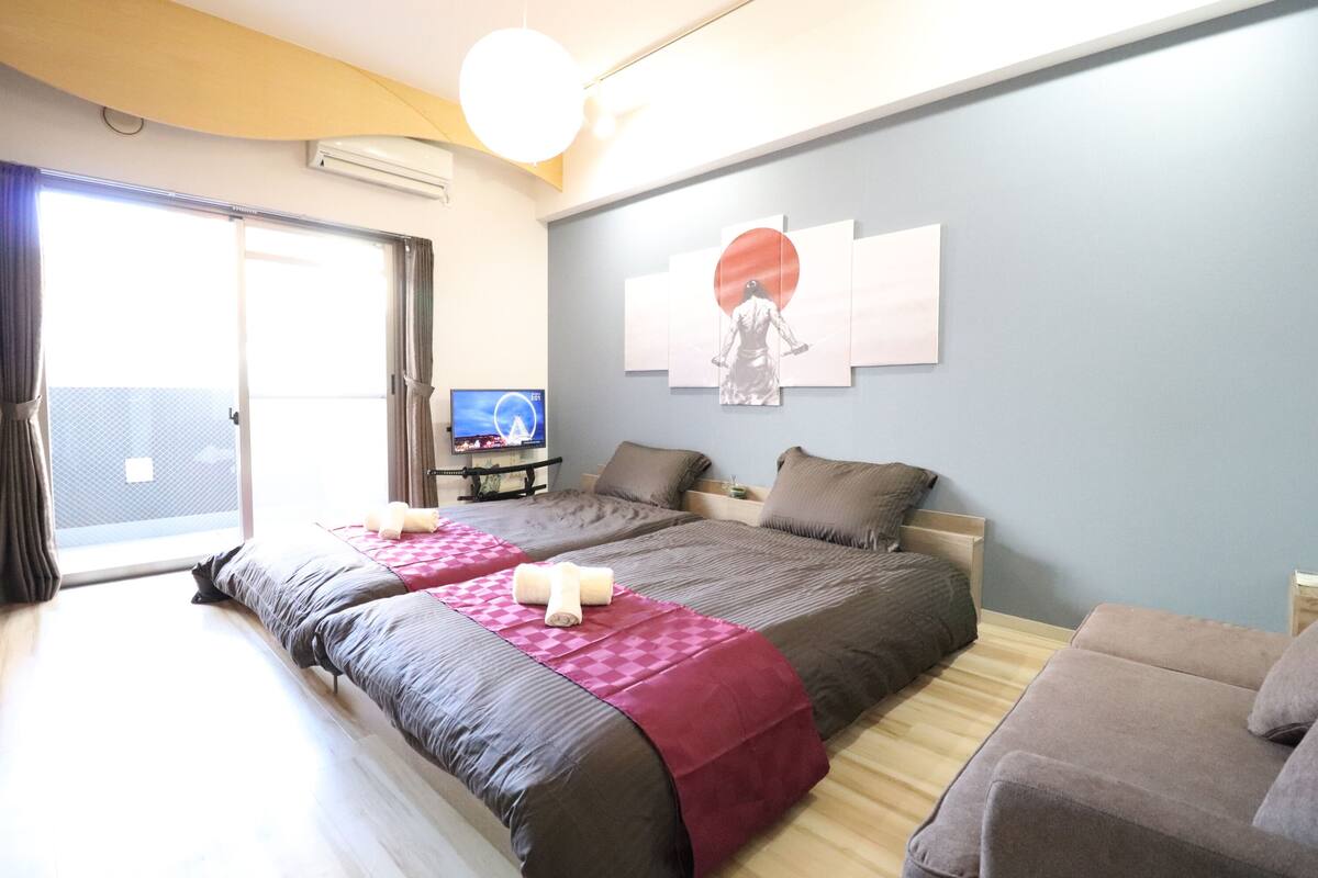 A bedroom with two beds, a TV, and a large window.