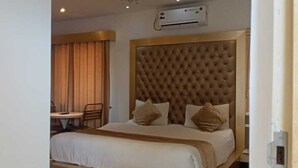 Een hotelkamer met een groot bed, een hoofdbord, een bureau en een stoel.