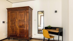 Ein Zimmer mit einem großen Holzschrank, einem Schreibtisch mit Stuhl und einem Spiegel an der Wand.
