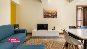 Ein modernes Wohnzimmer mit Flachbildfernseher, einer Couch, einem Esstisch und Stühlen.