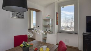 Un coin repas avec une table en bois, des chaises, une orchidée en pot et une lampe noire.