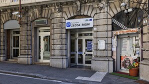La façade d’un immeuble porte une enseigne indiquant « Funicolare Zecca-Righi », et un magasin appelé « Funicolare » se trouve à proximité.