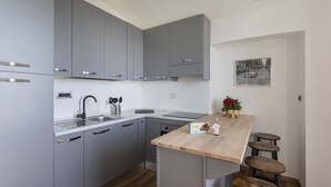 Une cuisine moderne avec des meubles gris, un plan de travail en bois et un petit coin bar avec des tabourets.