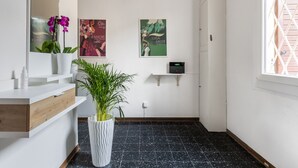 Uma casa de banho moderna com uma toucador branca, uma planta em vaso, um espelho e obras de arte nas paredes.