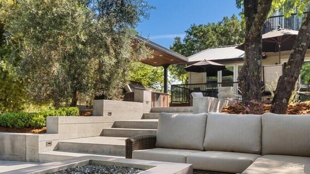 A modern outdoor seating area with a fire pit, cushioned seating, and a staircase leading to a covered patio. - Healdsburg Luxe Reserve for 8, pool, spa, firepit (Healdsburg)