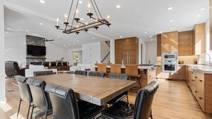 A modern kitchen with wooden cabinets, a built-in oven, and a dining area with a wooden table and leather chairs. - Healdsburg Luxe Reserve for 8, pool, spa, firepit (Healdsburg)