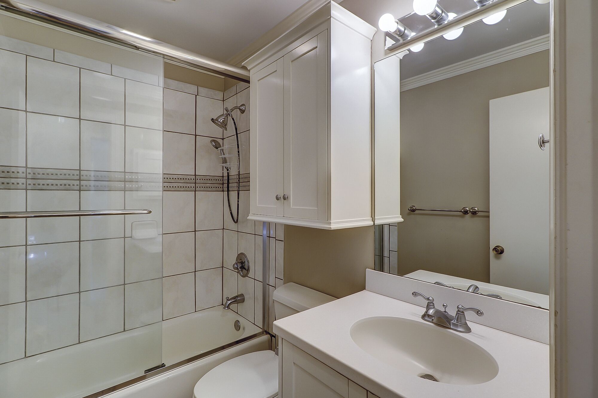 Un baño moderno con ducha envuelta en vidrio, un lavamanos blanco y un espejo grande.
