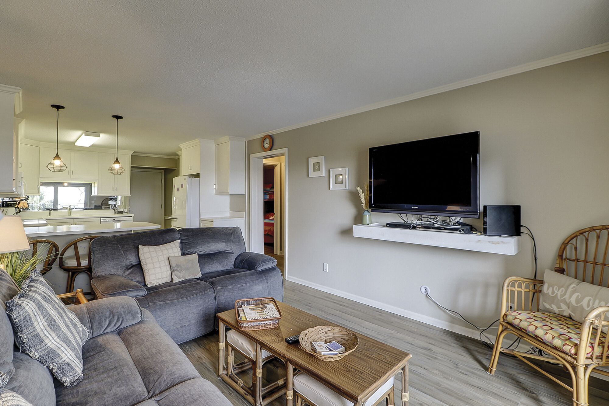 A living room with a grey sofa, a wooden coffee table, and a TV mounted on a white shelf.