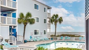 Ein Strandhotel mit Pool, Liegestühlen und Palmen.