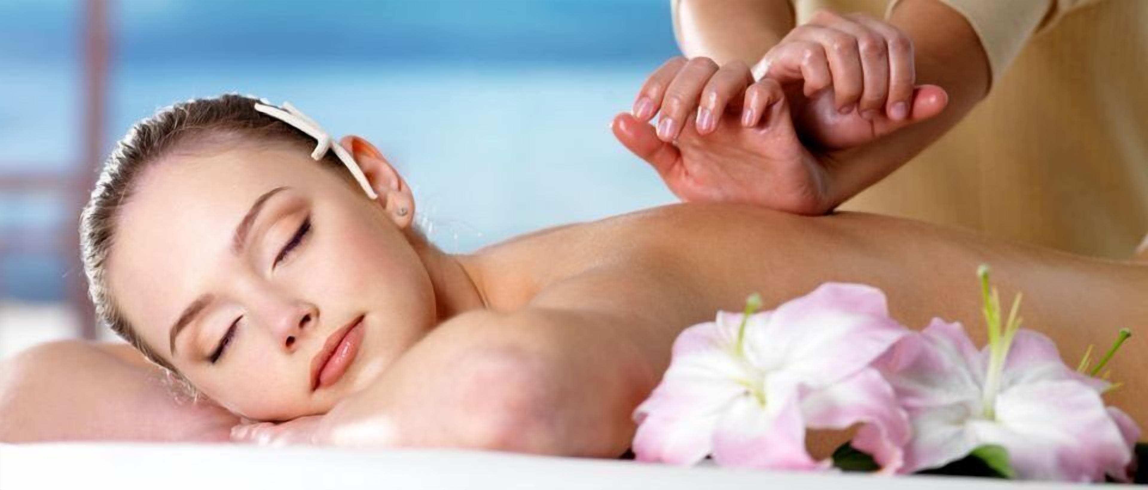 Une personne reçoit un massage, et il y a des fleurs sur la table.