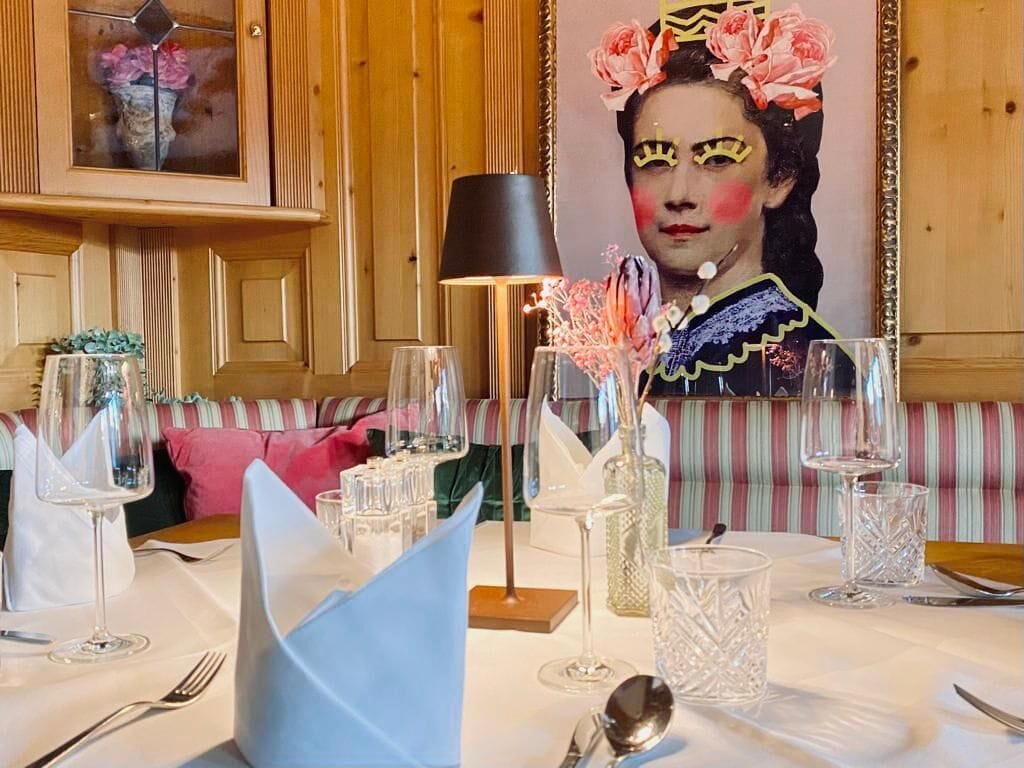 Una mesa de comedor dispuesta con cristalería, un florero con flores y una vela.