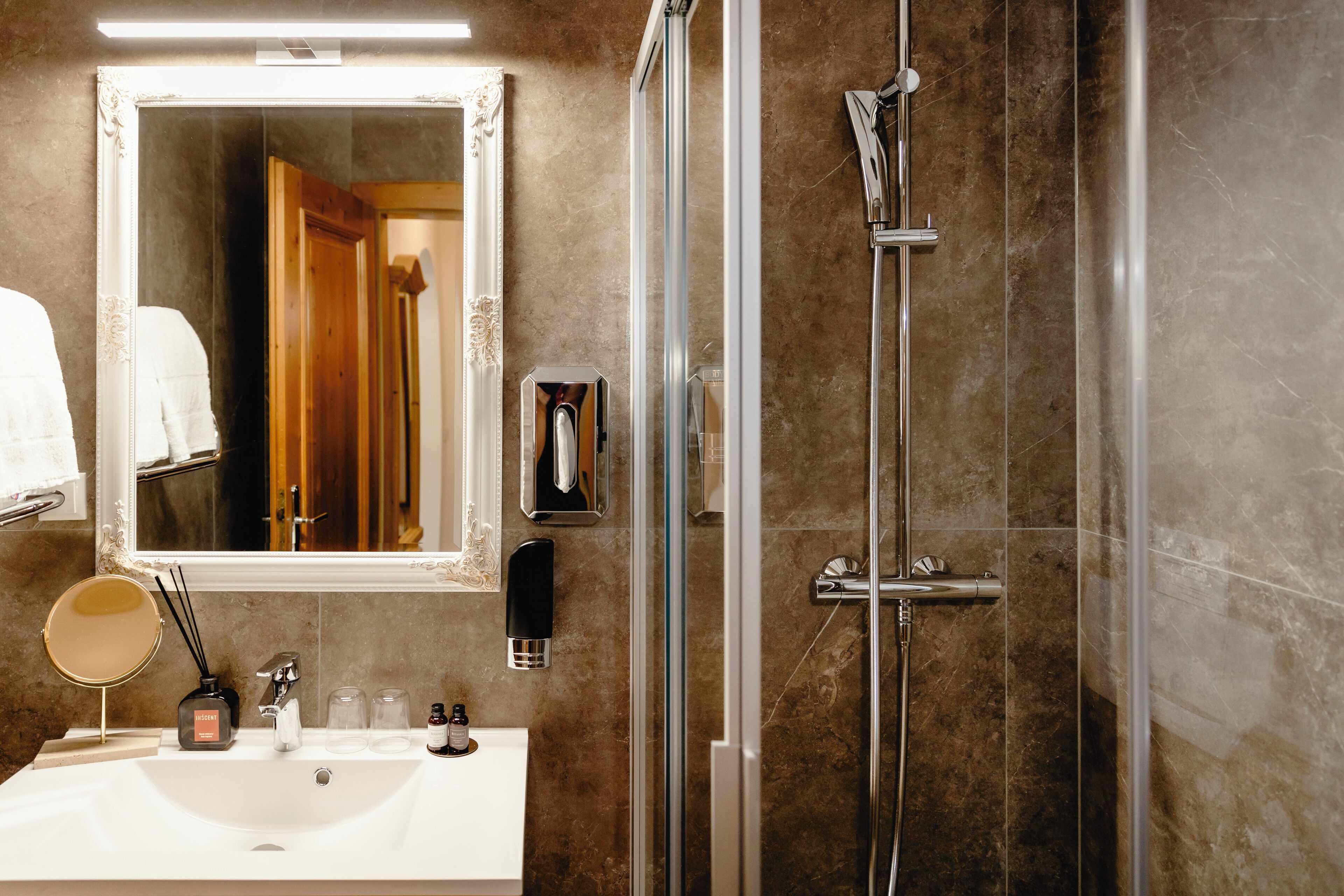 A bathroom with a sink, mirror, and shower.