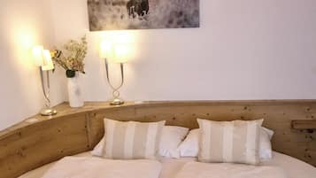 Un lit double avec deux oreillers, une tête de lit en bois et un tableau représentant un cerf accroché au mur.