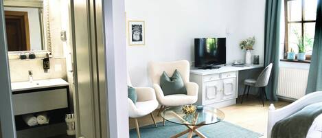 Una sala de estar moderna con una mesa de centro de vidrio, un sofá, un televisor y un escritorio con una computadora.