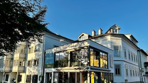 A corner building with large windows and a glass entrance. - Boutiquehotel Hubertushof (Bad Ischl)