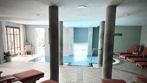 A pool area with lounge chairs and a tiled floor. - Boutiquehotel Hubertushof (Bad Ischl)