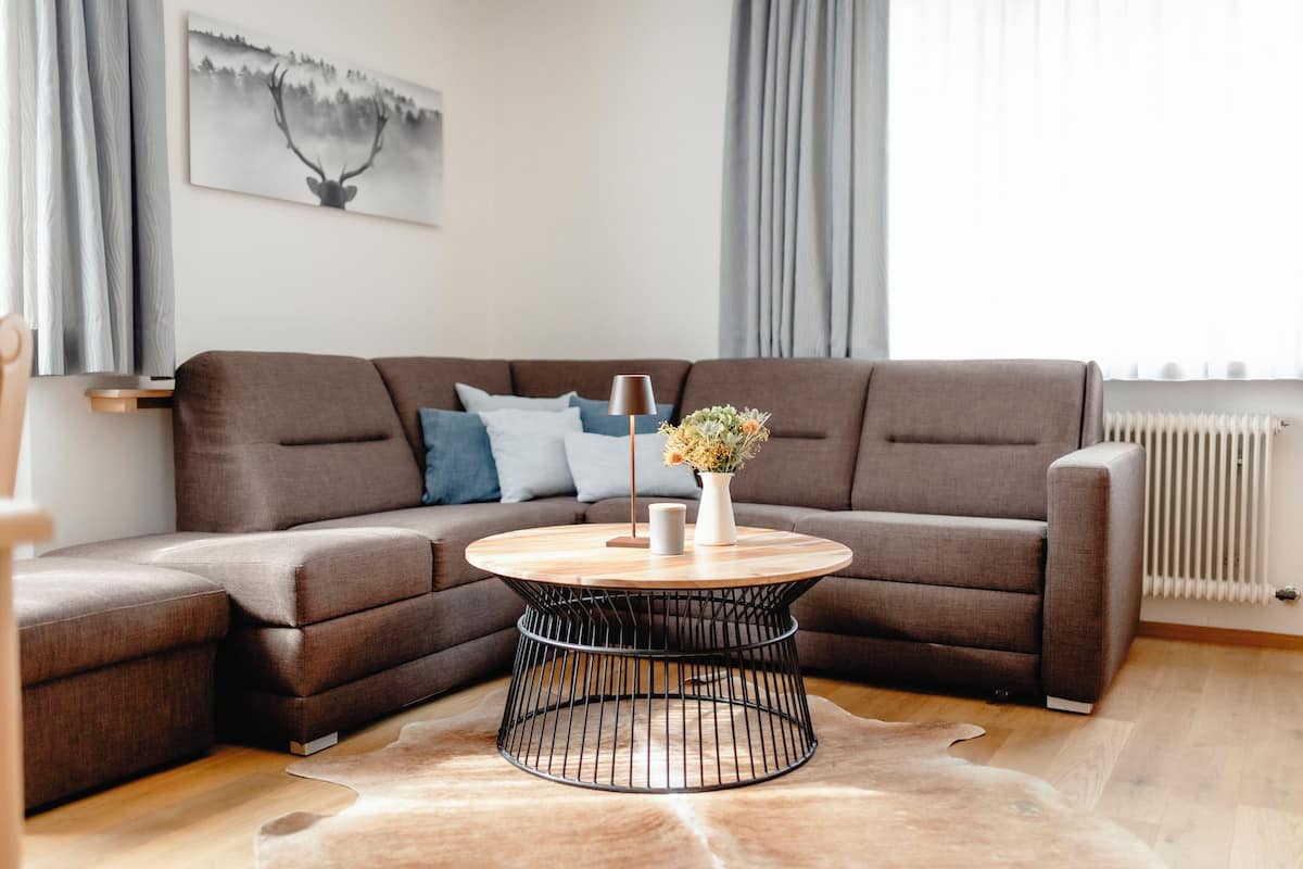 A modern living room with a sectional sofa, a round coffee table, and a decorative vase.