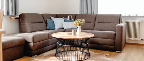 A modern living room with a sectional sofa, a round coffee table, and a decorative vase.
