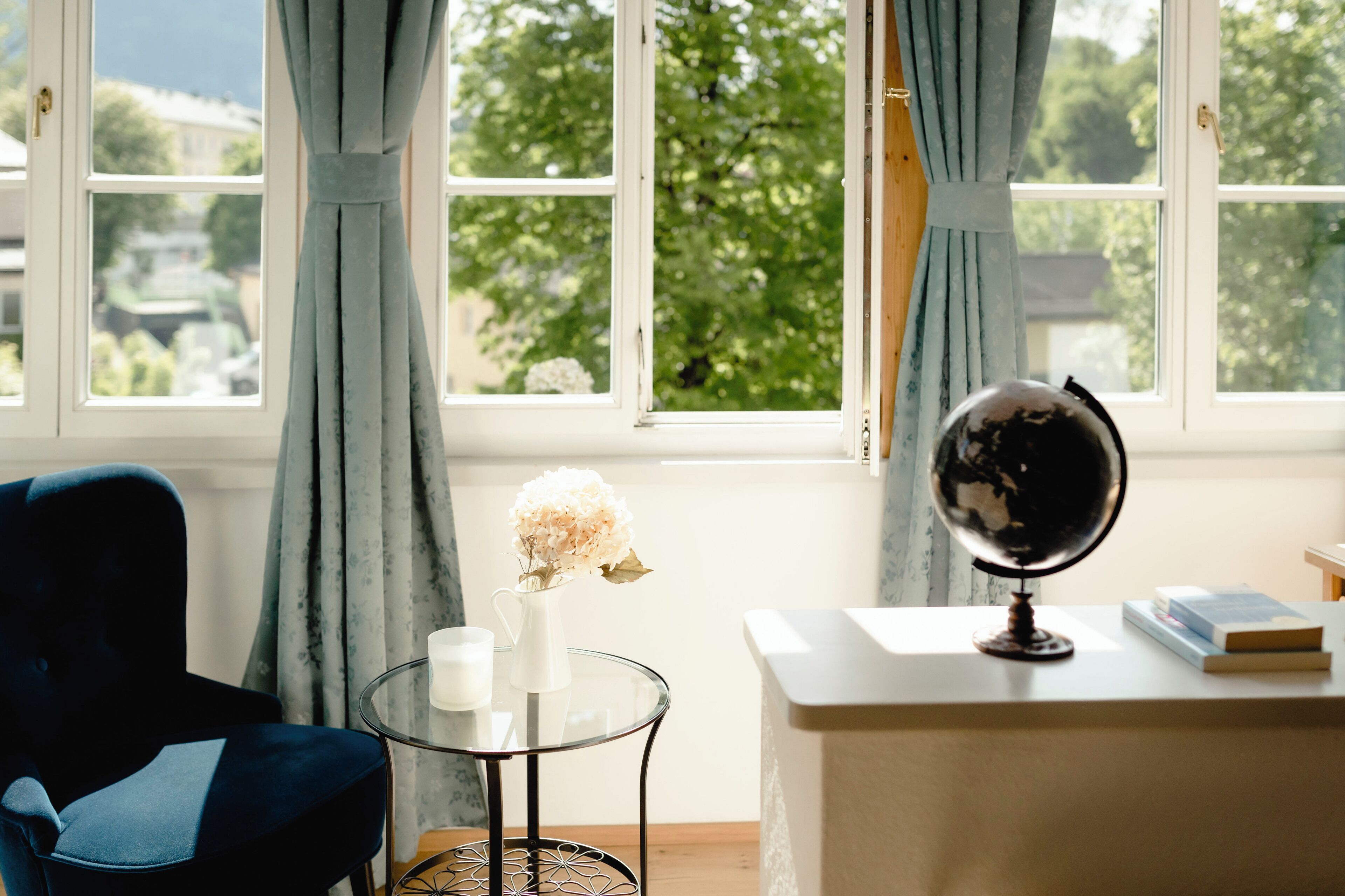 A room with a desk, a globe, a vase with flowers, and a chair.