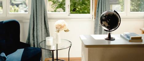 A room with a desk, a globe, a vase with flowers, and a chair.