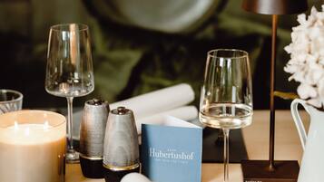 A table set with a candle, salt and pepper shakers, a folded napkin, a glass of water, a wine glass, and a menu.