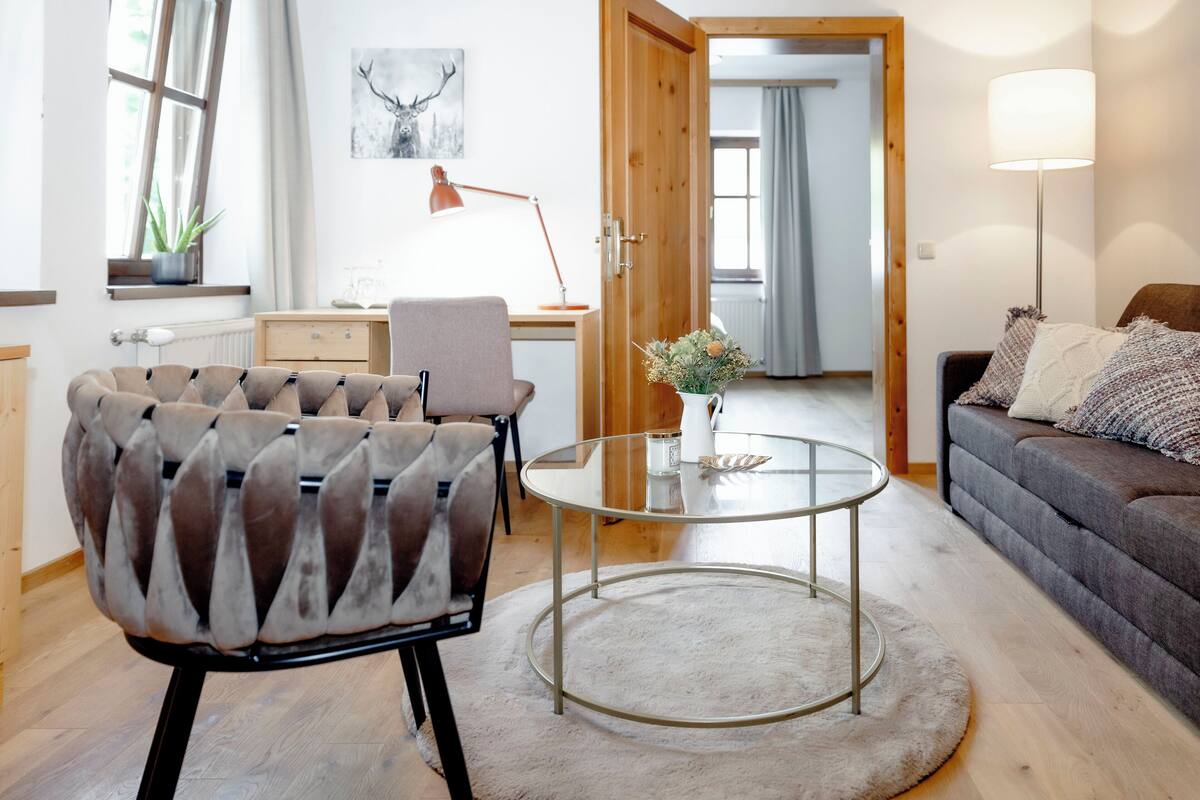 A modern living room with a round glass coffee table, a sofa, a chair, and a lamp.
