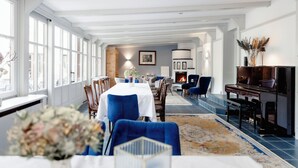 A spacious dining area with a long table, blue upholstered chairs, and a fireplace. - Boutiquehotel Hubertushof (Bad Ischl)