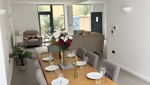 Un comedor moderno con una mesa de madera dispuesta para seis personas, rodeada de sillas grises tapizadas.