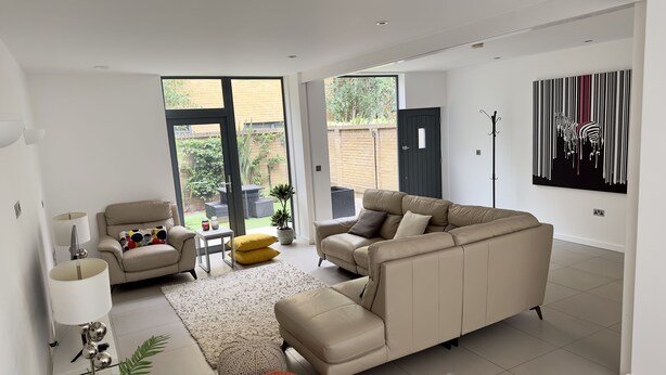 Una sala de estar moderna con un sofá color beige, una mesita y una lámpara de pie.