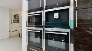 Una cocina moderna con cuatro hornos empotrados y un microondas.