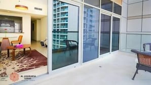 A modern apartment with a balcony, a dining area, and a kitchen visible through glass walls. - Charming apartment in Sport city (Dubai)