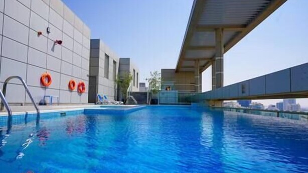 An indoor swimming pool with clear blue water, surrounded by a modern building with a tiled facade. - Charming apartment in Sport city (Dubai)