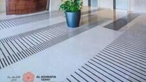 A modern lobby with a reception desk, a large potted plant, and a patterned floor. - Charming apartment in Sport city (Dubai)