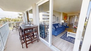 Un balcone con tavolo e sedie in legno, un divano blu e vista su un edificio con balconi.