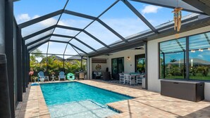 A covered outdoor swimming pool with a patio area, a grill, and a seating arrangement. - Coral Breeze  | Sunshelf | 4 Bed, 3 Bath (Rotonda West)