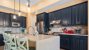 A modern kitchen with dark cabinets, stainless steel appliances, and a central island with seating. - Coral Breeze  | Sunshelf | 4 Bed, 3 Bath (Rotonda West)
