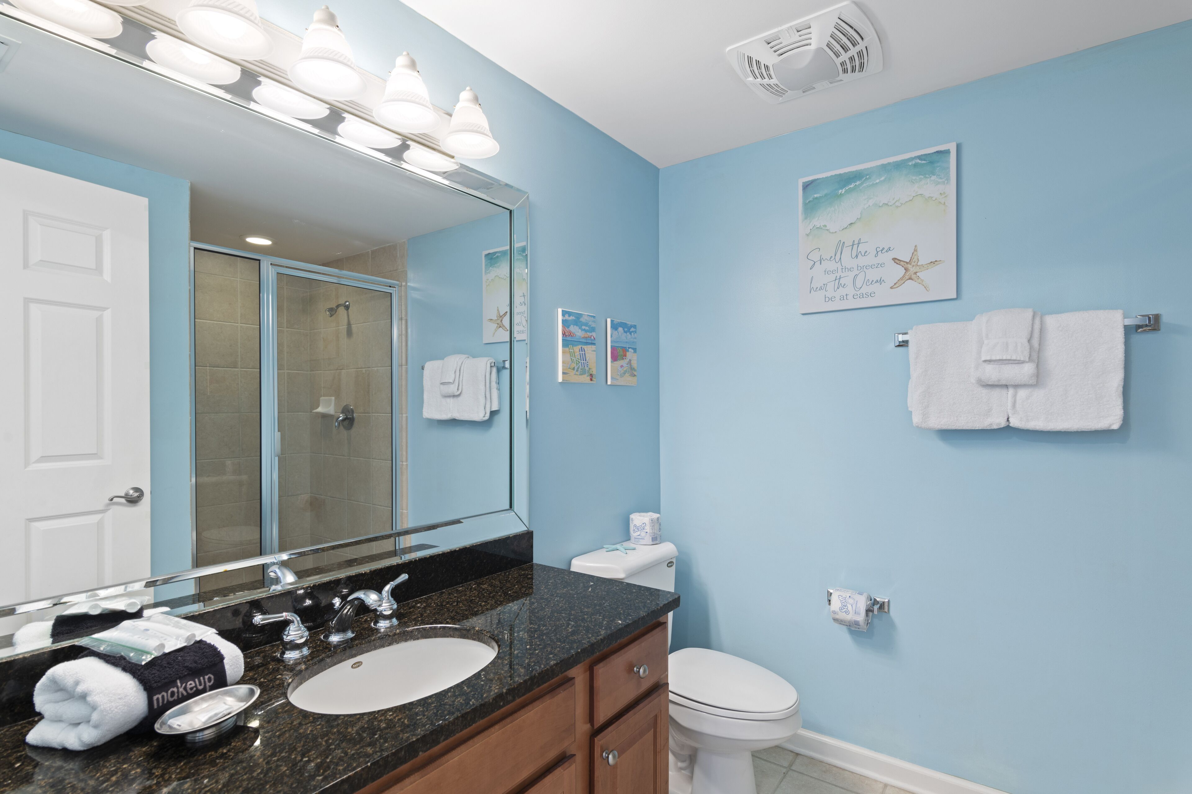 Une salle de bain avec un grand miroir, un lavabo, des toilettes et une douche.