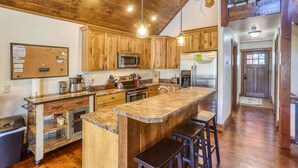 A kitchen with wooden cabinets, a granite countertop, and a bar stool. - Stem Winder Lodge - Wifi, A/C, Hot tub (Lead)
