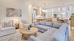 A spacious living room with a large gray sectional sofa, a round coffee table, and a white armchair. - Special Lakeside Home @ Cinnamon Shore South w/Access to On-Site Amenities (Port Aransas)