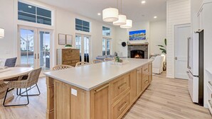 A spacious kitchen with a large island, wooden cabinets, and a fireplace. - Special Lakeside Home @ Cinnamon Shore South w/Access to On-Site Amenities (Port Aransas)