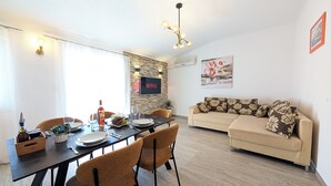A modern living room with a dining area, a sofa, a TV, and a fireplace. - Easy City Access: 3BR w/ Balcony & Private Carport (Zadar)
