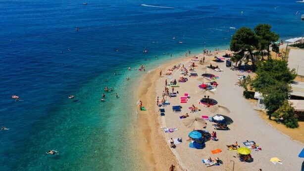 A beach with clear blue water, people swimming and sunbathing, and umbrellas on the sand. - Easy City Access: 3BR w/ Balcony & Private Carport (Zadar)