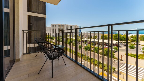 Ein Balkon mit einem Stuhl und Blick auf eine Straße sowie Gebäude im Hintergrund.