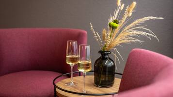 Dos copas de vino blanco sobre una mesa redonda con un florero de plantas secas.