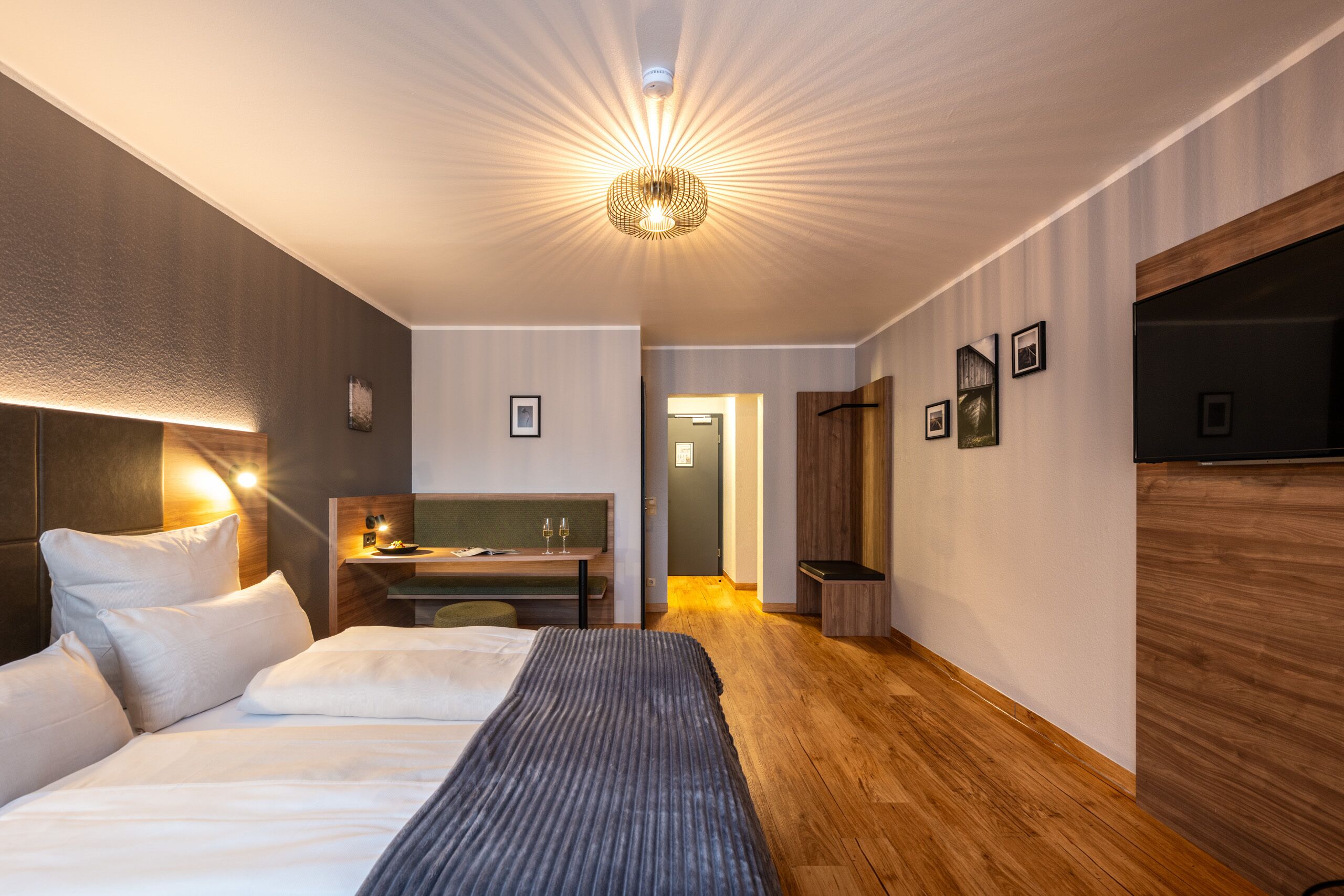 A modern hotel room with a large bed, a desk, and a television.