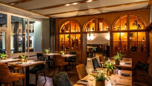 A restaurant with wooden interiors, tables set for dining, and arched display cabinets with bottles. - Uferdeck - Boutique Hotel (Traben-Trarbach)