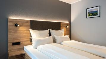 Een moderne hotelkamer met een groot bed, een houten hoofdbord en een wandlamp.