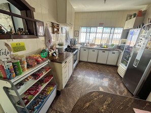 A kitchen with a refrigerator, sink, and various food items on shelves. - Rota BH Hostel (Belo Horizonte)