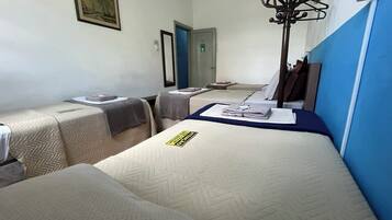 A hotel room with two single beds, a large mirror, a coat rack, and a door to another room.
